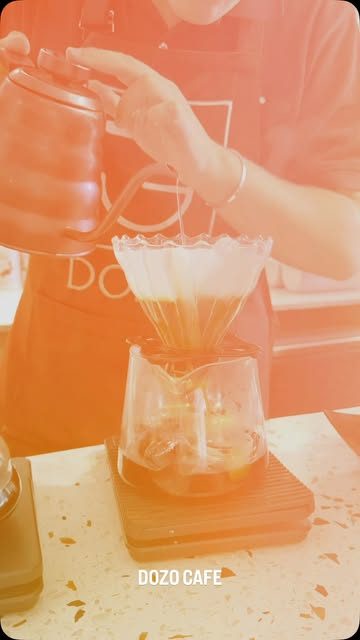 A barista pouring a V60 into a glass carafe